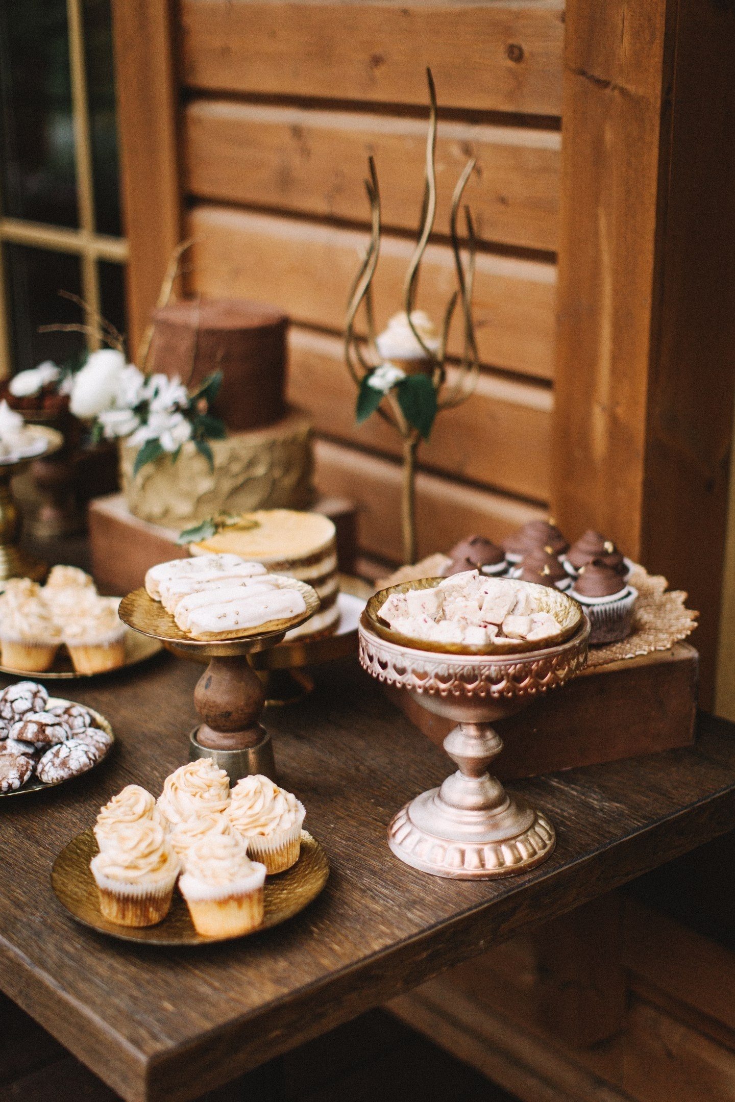 Broken bars of chocolate, truffles, mocha airy desserts, decorated with coffee beans and openwork cookies with icing in a wedding style look great in the company of aged boxes and ornate stands